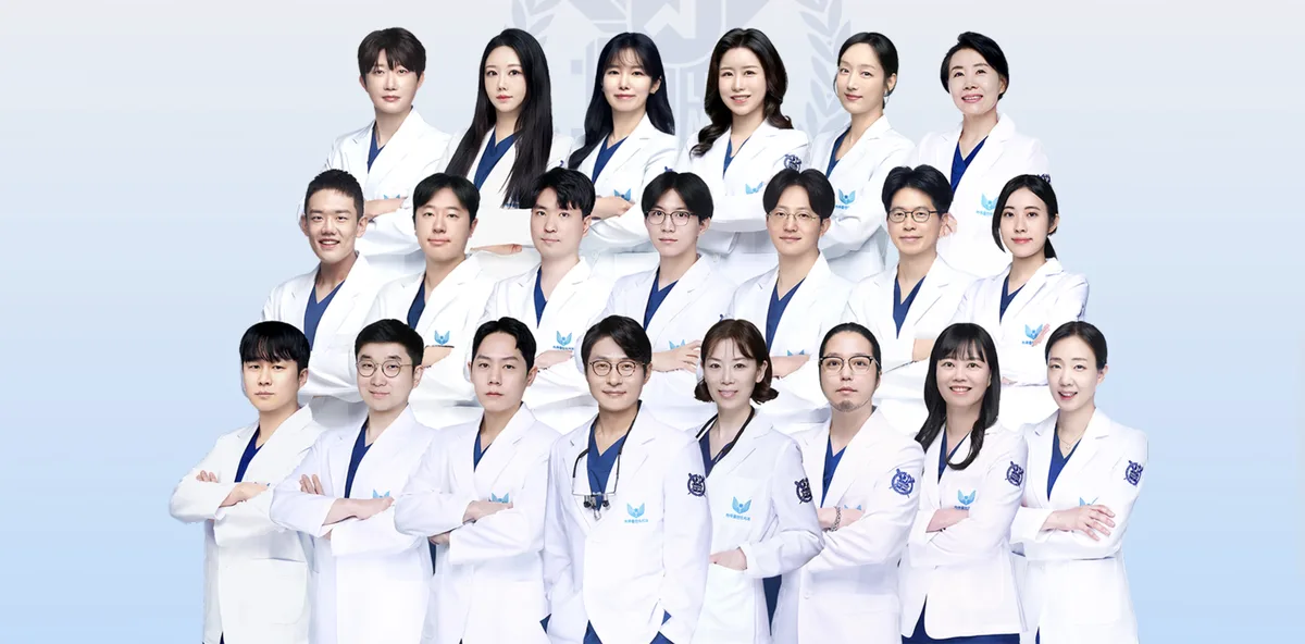 하루플란트치과의원 의료진 단체 사진, 흰 가운과 남색 스크럽을 입은 의료진이 세 줄로 서서 팔짱을 끼고 정면을 보는 모습